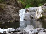 La fine chute qui se jette dans un bassin semi-artificiel d'eau transparente.